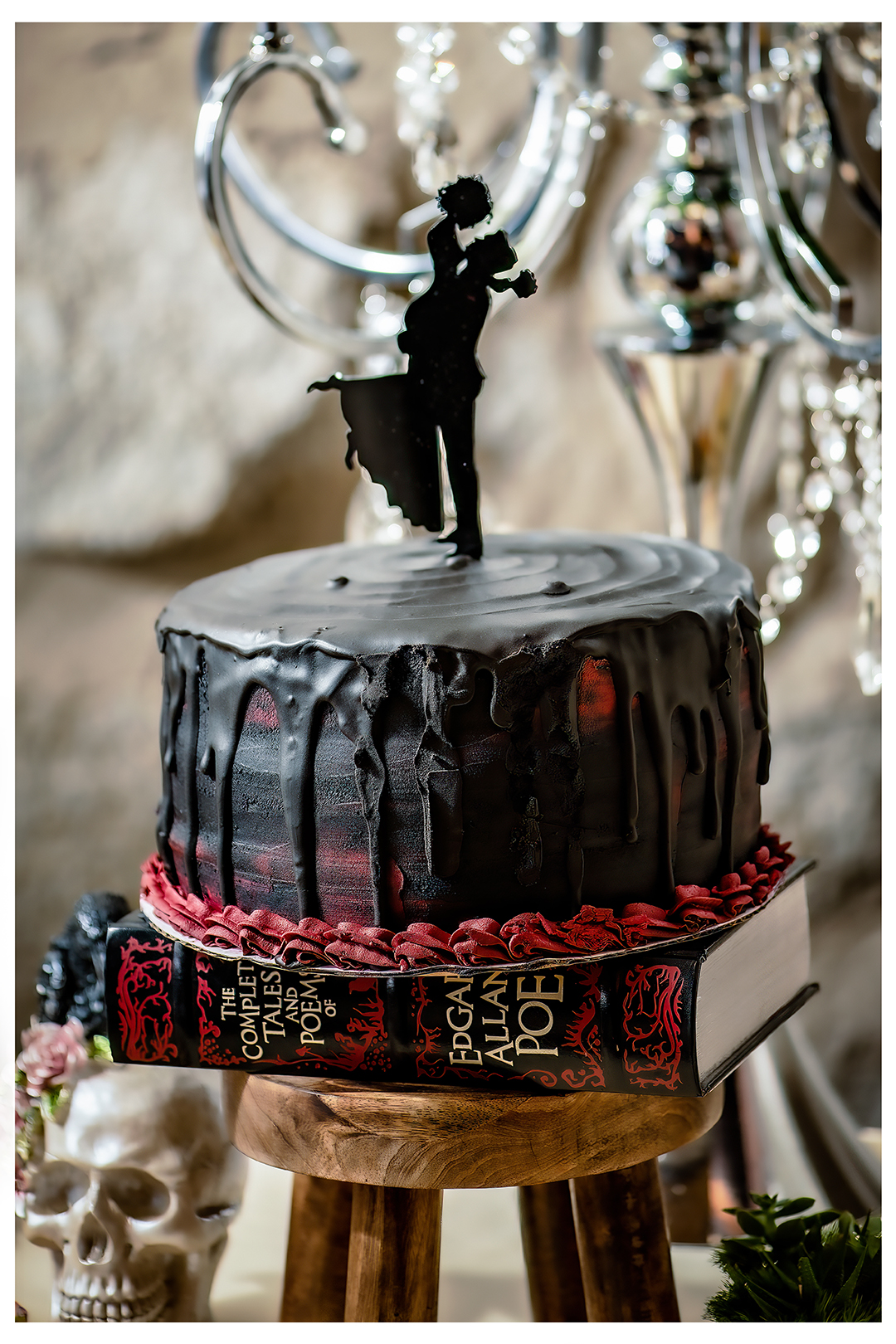 Edgar Allan Poe Cake at Château Rive. The cake is sitting on a Edgar Allan Poe book and short stool stand with a silhouette of a couple on their wedding day. 