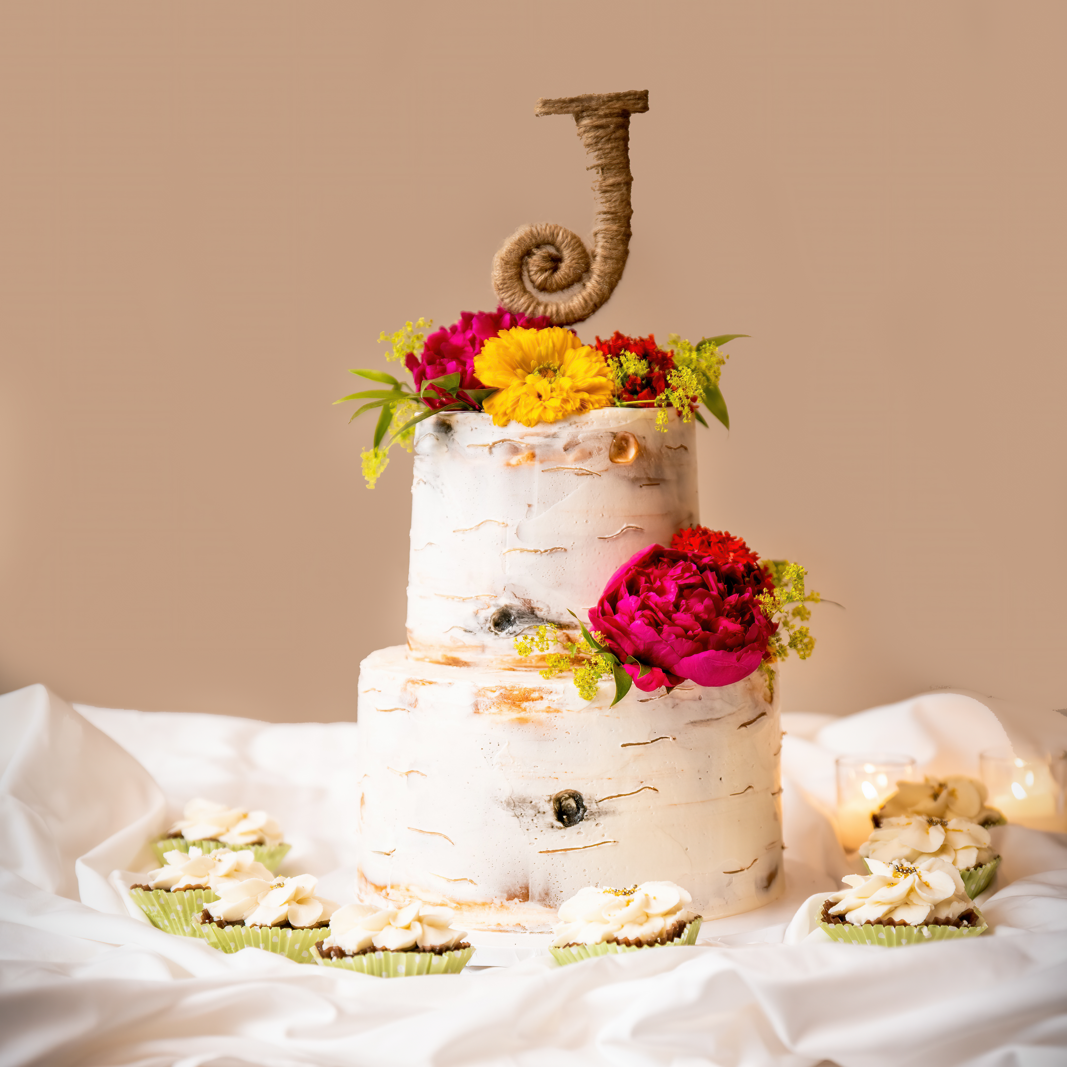 Wedding cake with a "J" on the top. That has a look like a piece of wood stump with yellow and pink flowers. 