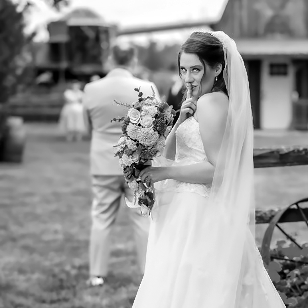 Bride getting ready to surprise the groom during their first look before the ceremony. She is holding a bouquet of flower wearing a long flowing veil. 