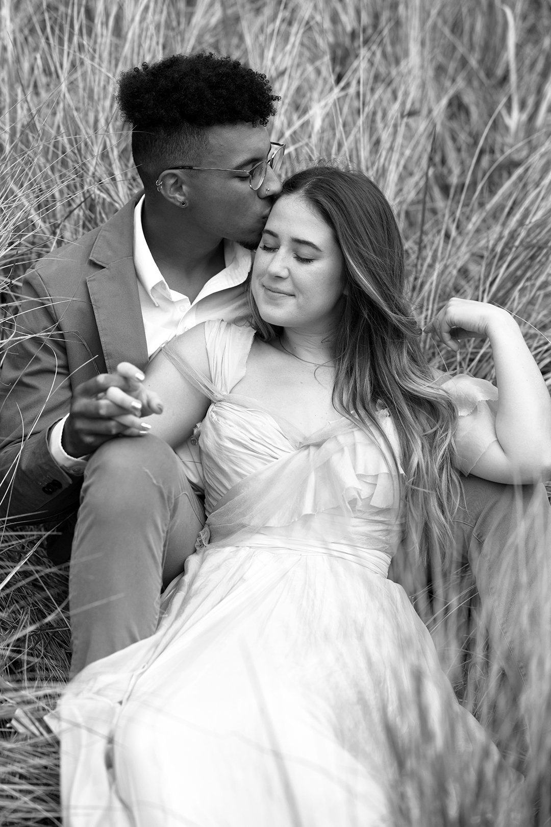 A couple sitting in tall grass at the Oregon Coast.