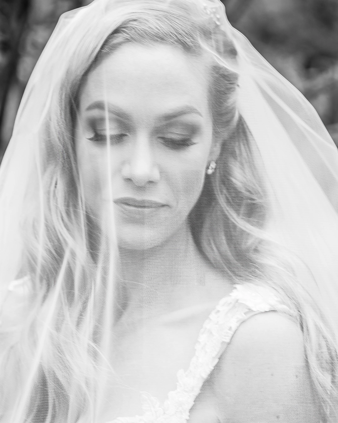 Black and White photo of bride under a veil with her eyes looking down. 