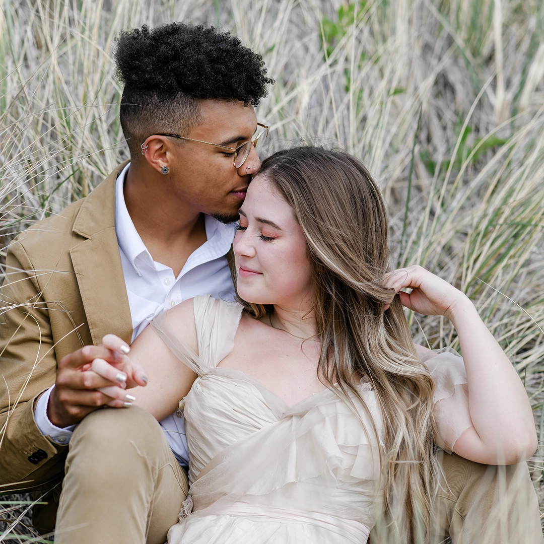 Couple sitting in beach grass near Cannon Beach. 