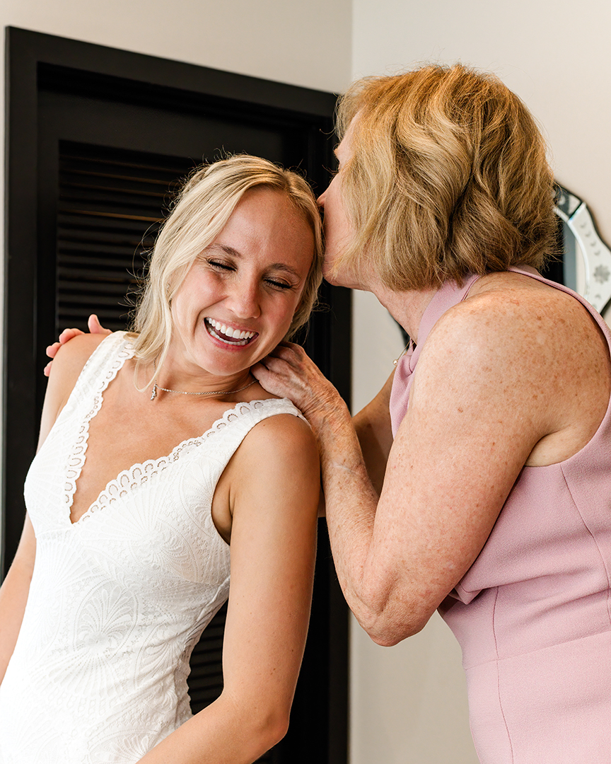 Mother of the Bride kissing Bride on the forehead while getting ready. 
