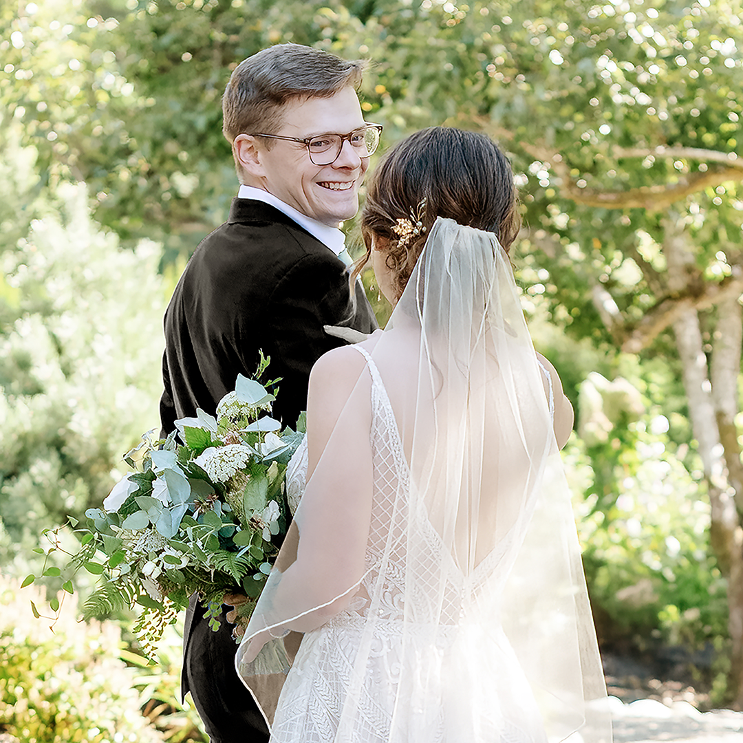 Groom turning to see the bride for the first time smiling as he sees her. 