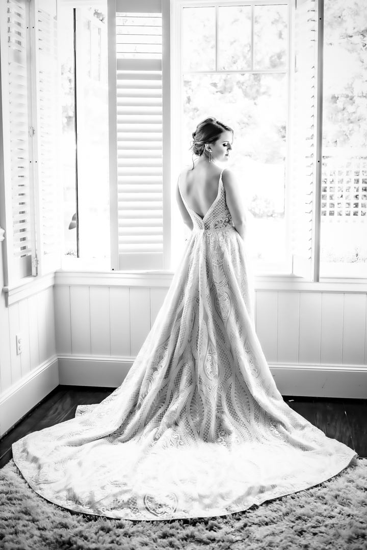 Bride stands at a bright window, taking a moment before the first look on her wedding day. 