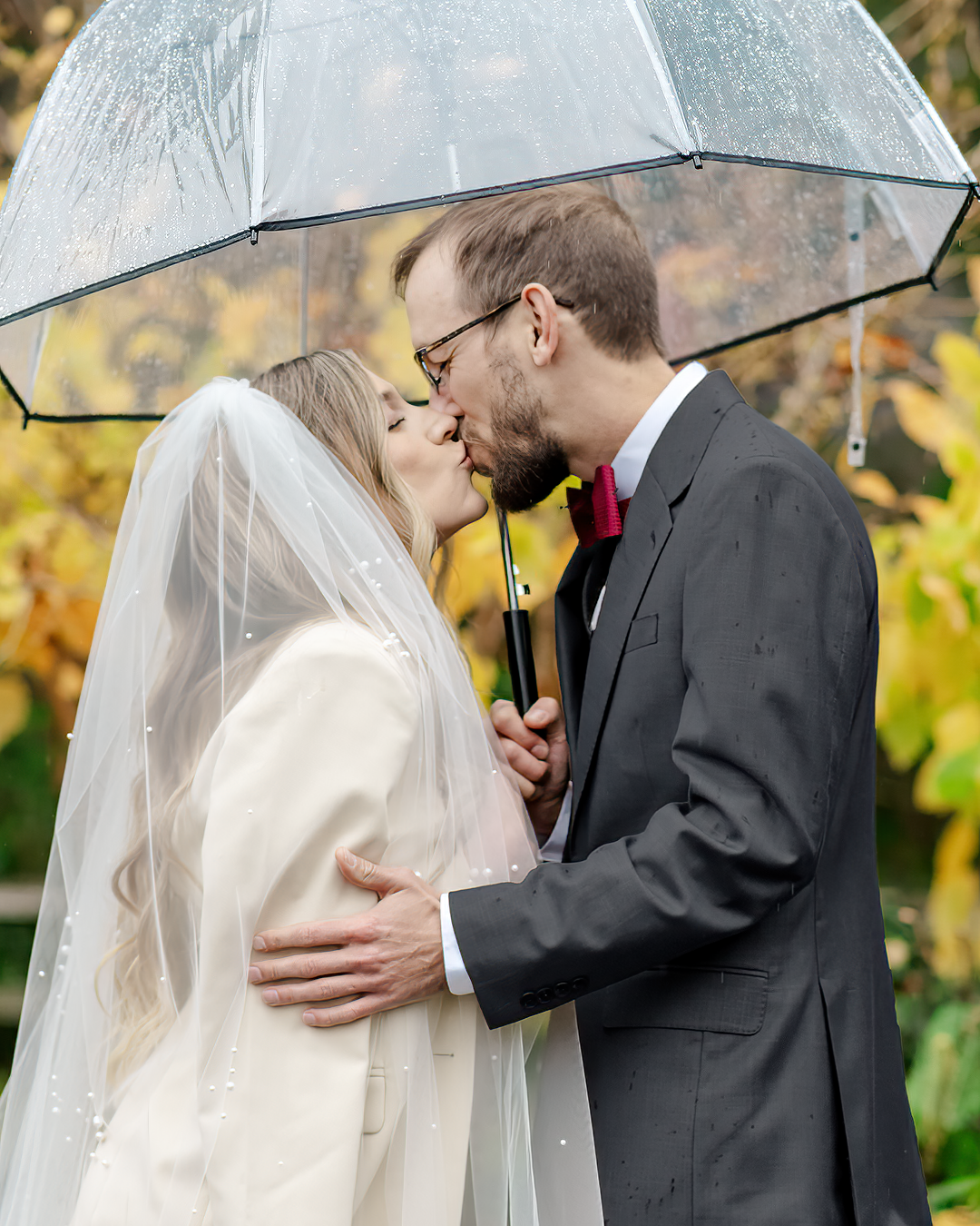 A couple does their first look under an umbrella on a rainy wedding day.