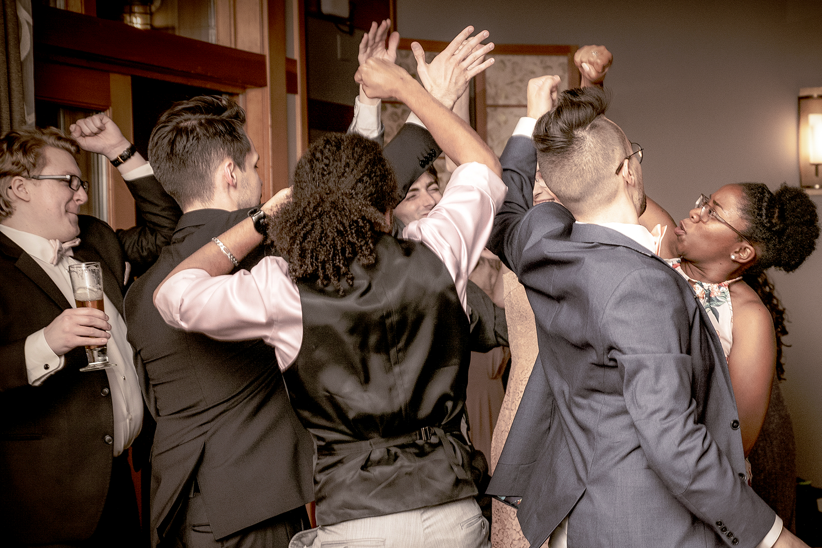 Crowd dancing at a wedding in the Seattle area with hands up in the air and enjoyin the music at the reception.