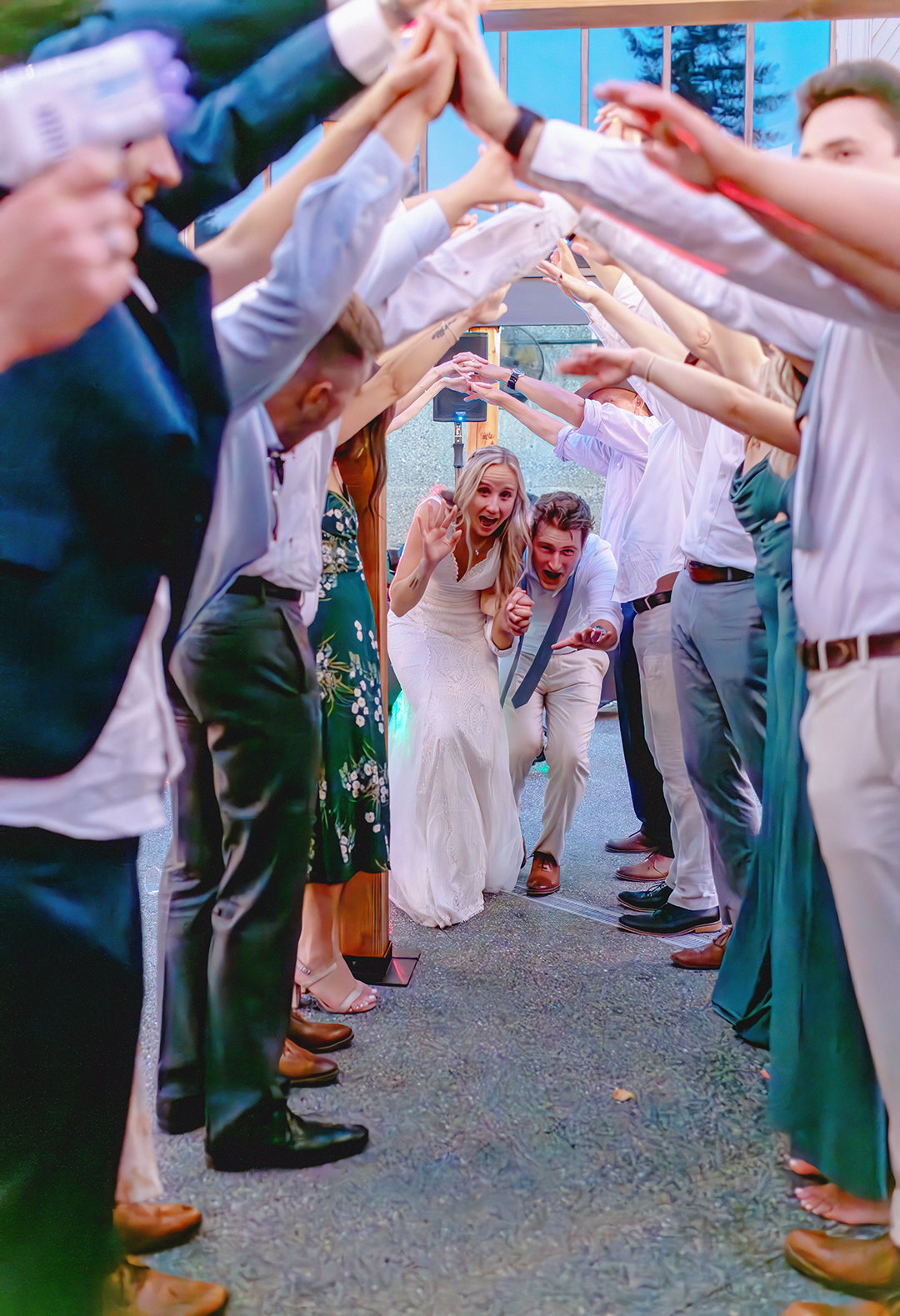 Reception lighting while a couple runs through a tunnel of friends with raised hands for their grand exit. 