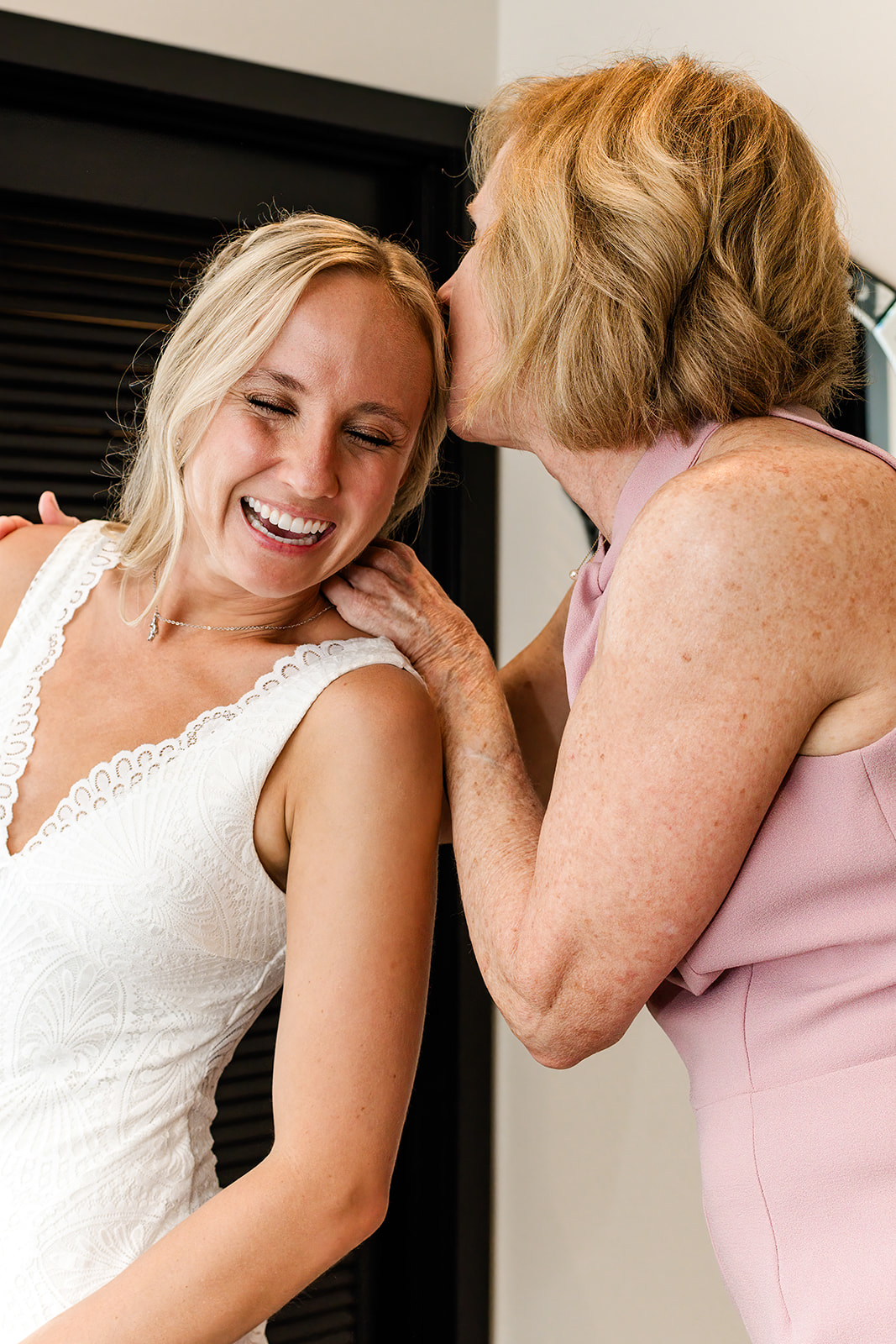 Mother of the bride kisses the bride's cheek after putting her veil in her hair. 