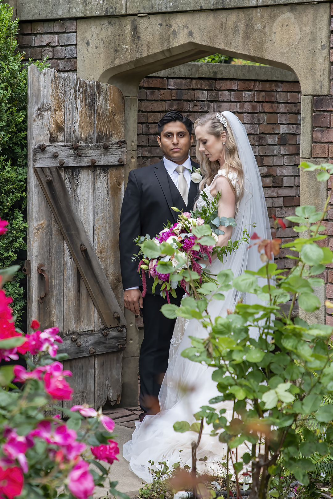 Couple stands at the garden gate entrance to the Secret Garden. 