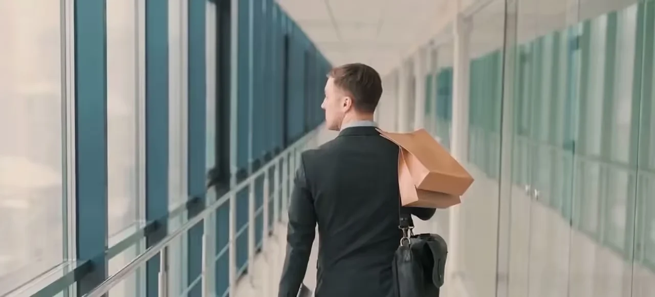 Empresário caminhando por um corredor com seus pertences, começando um novo caminho