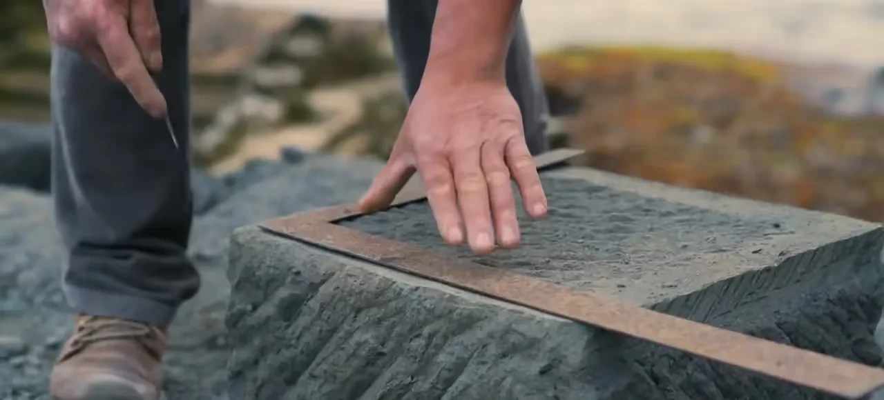 Mão alinhando uma base de pedra com precisão
