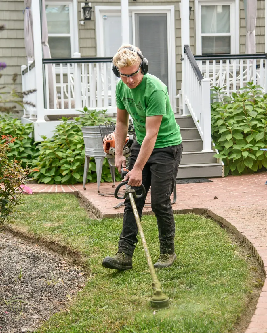Profissional de jardinagem aparando o gramado de uma casa