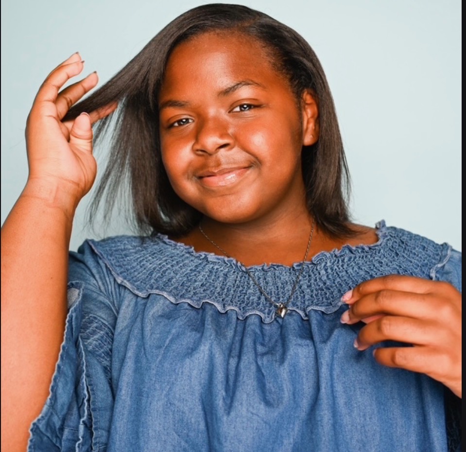 Tyli smiling softly, hand in her hair