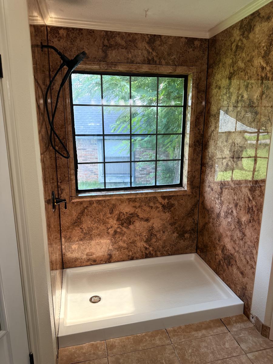 Finished walk-in shower with stone-look wall panels and a window