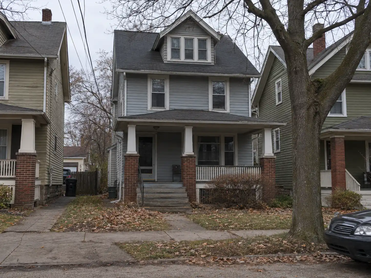 Early-1900s wood frame single family house in Lakewood, Ohio with a covered front porch on brick piers and a narrow shared driveway