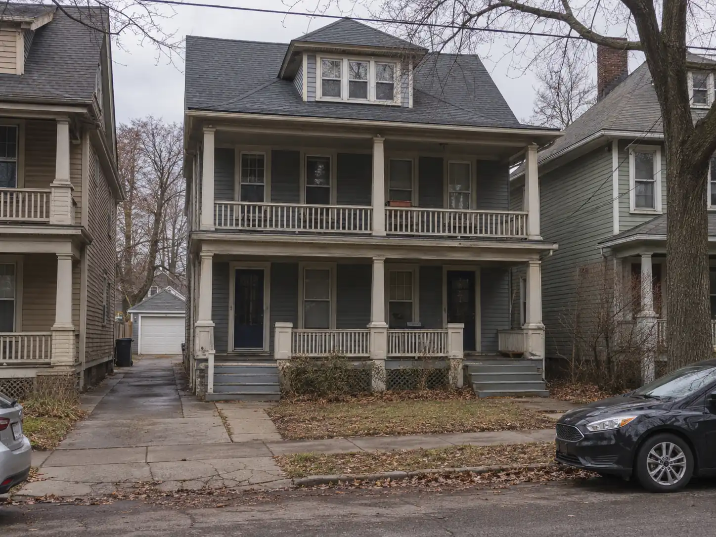 Lakewood two-family double with stacked upper and lower front porches, two separate entrances and a shared driveway to a rear garage
