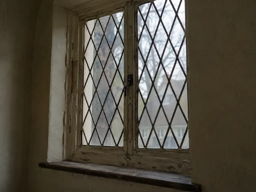 Original leaded glass diamond-pane casement window with peeling paint in a 1920s Heights house