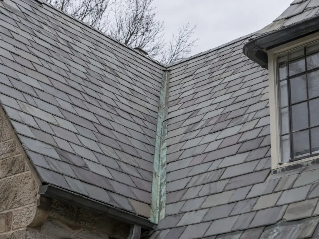 Aging slate roof valley with weathered copper flashing on a 1920s Heights house