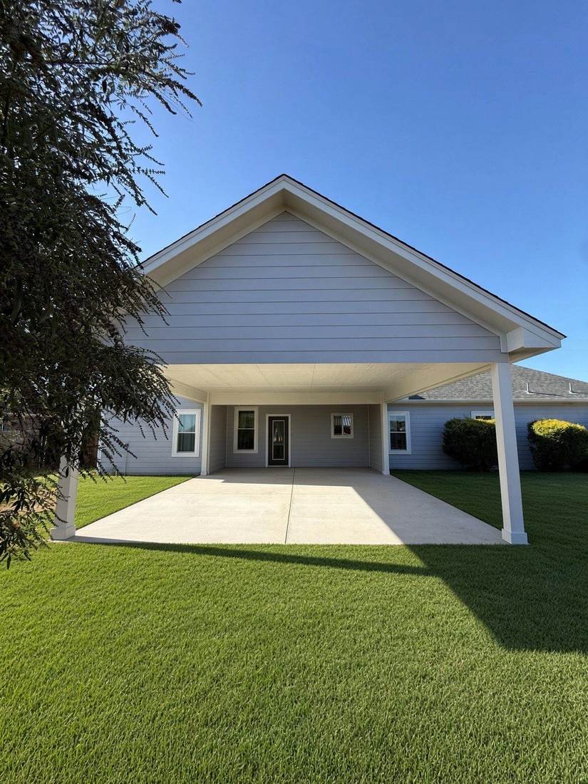 Gable-roof patio cover centered on the back of a home with a green lawn