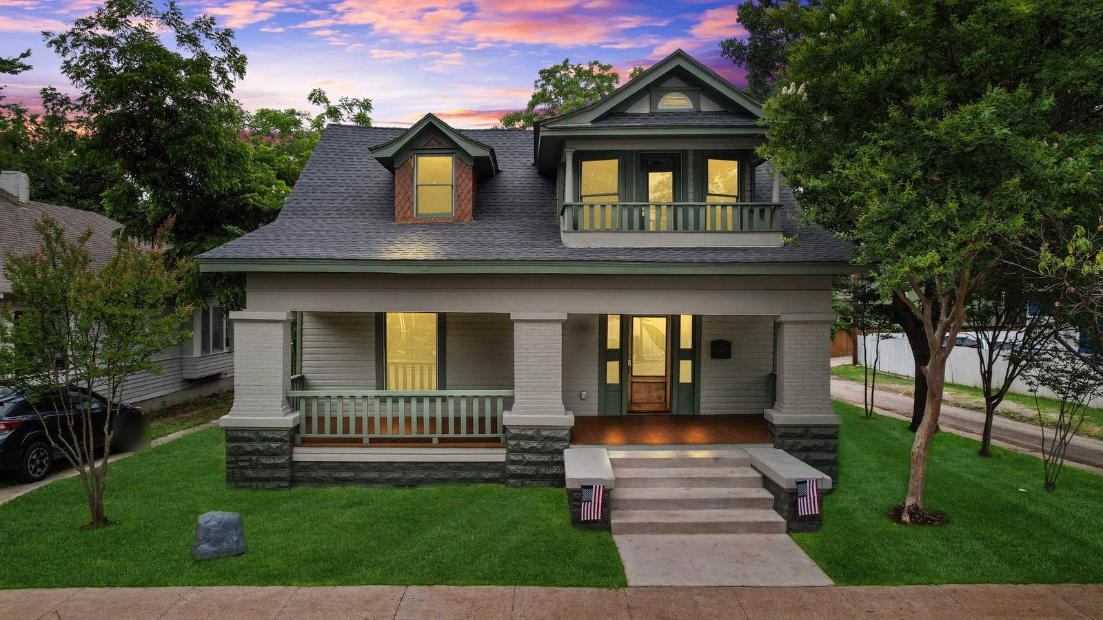 Historic Fort Worth home rebuilt by Zeus Exteriors, shown at dusk with custom-milled wood siding, new windows and a full front porch