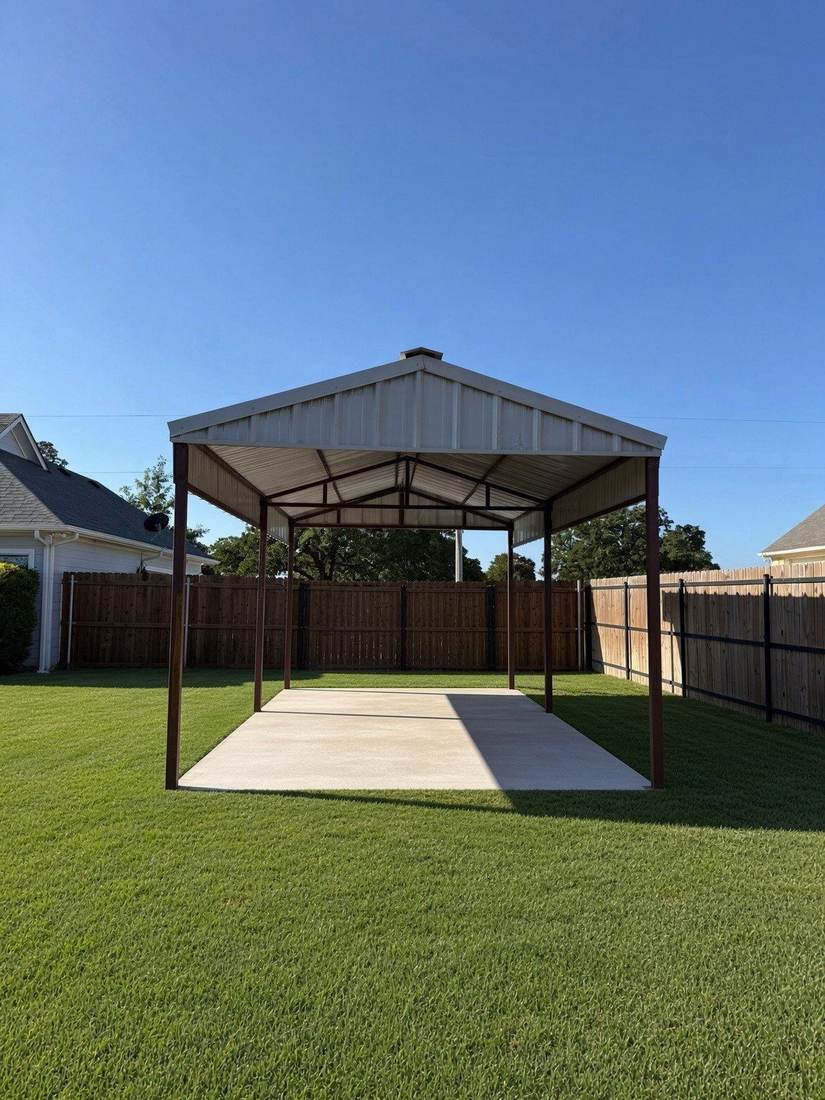 New metal carport over a concrete slab in a fenced backyard with green grass