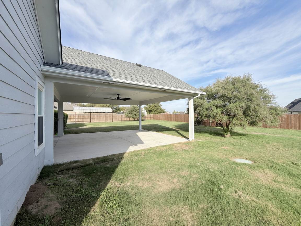 New white seamless gutter and downspout along the roofline of a new covered patio on a North Texas home