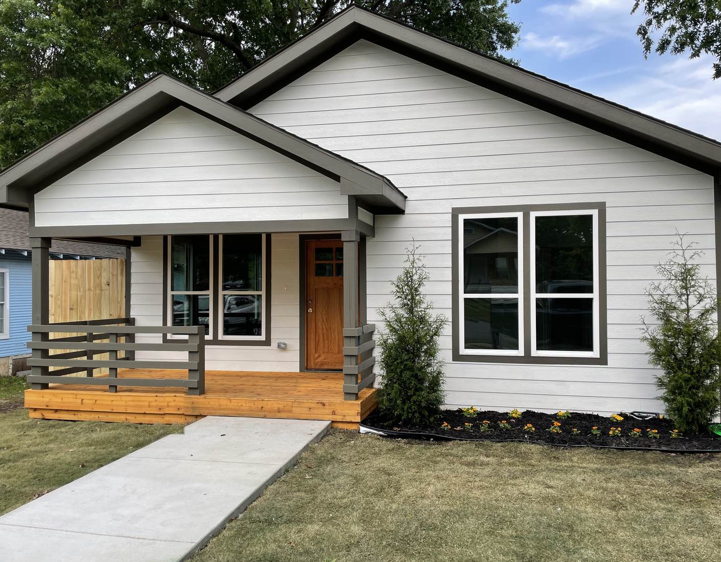 Custom home with new white lap siding, gray trim and a cedar front porch in North Texas