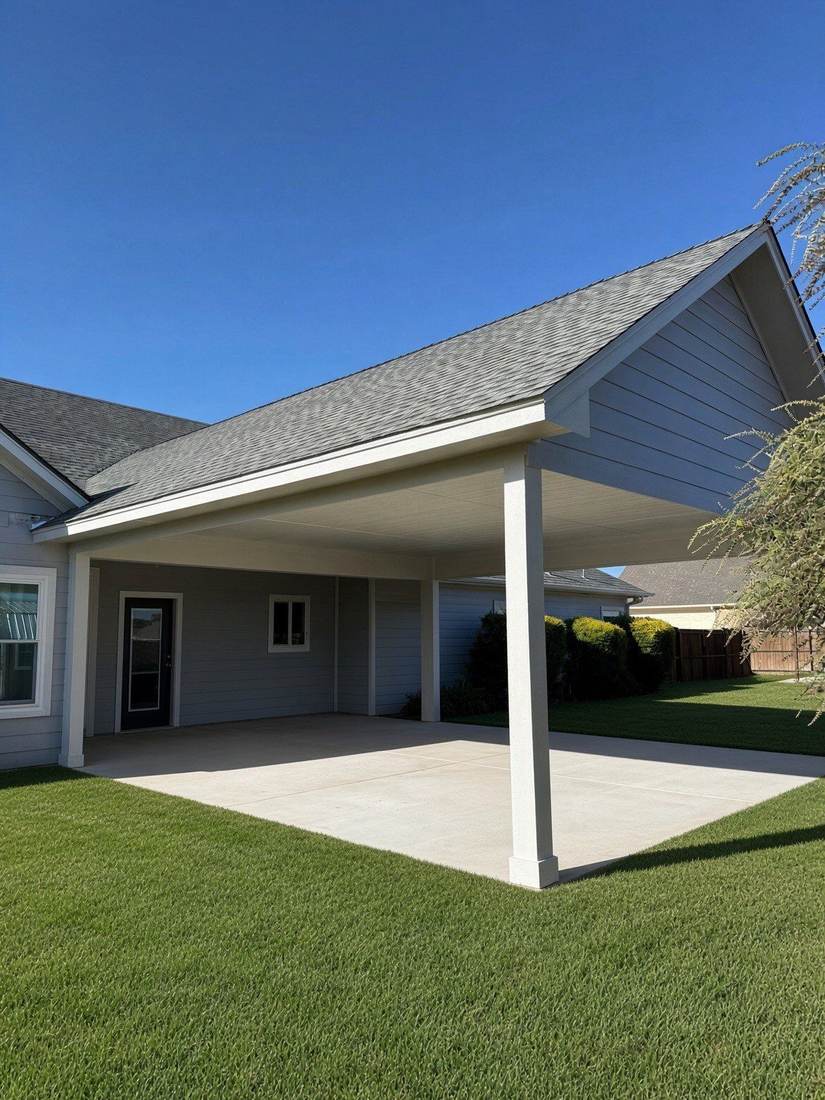 New covered patio extending the roofline of a home over a concrete slab