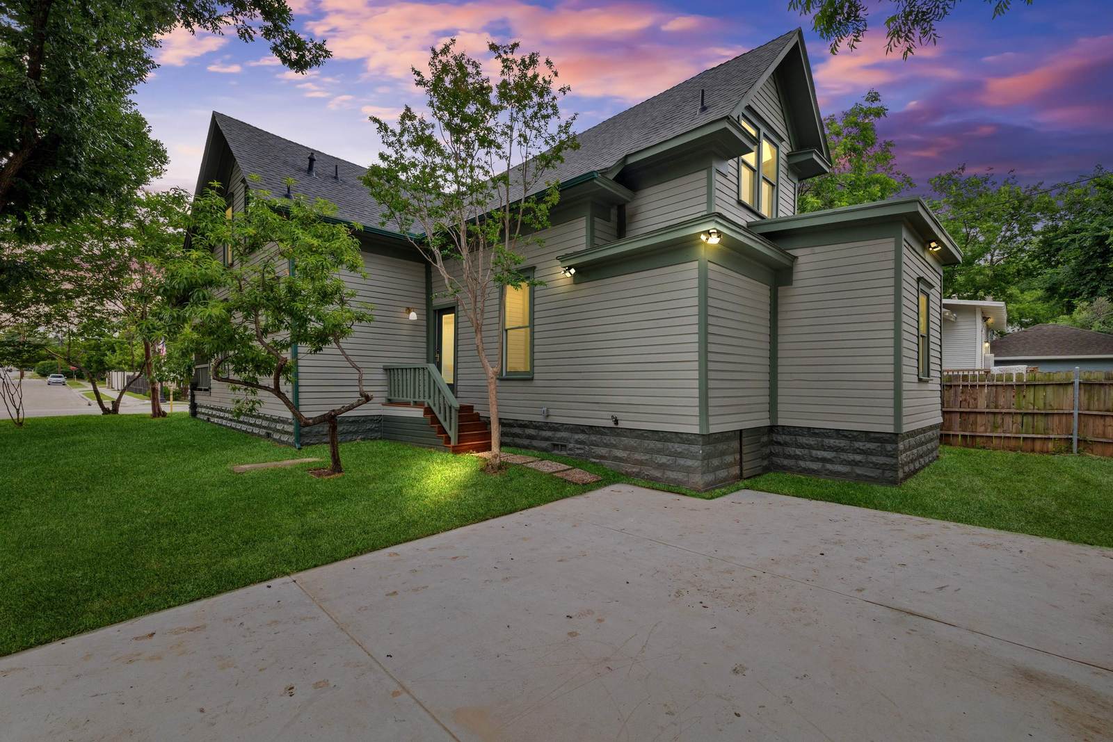 New concrete driveway beside a rebuilt historic home in Fort Worth at dusk