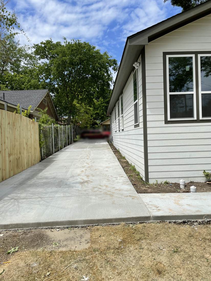 New concrete driveway running alongside a home with new lap siding in North Texas