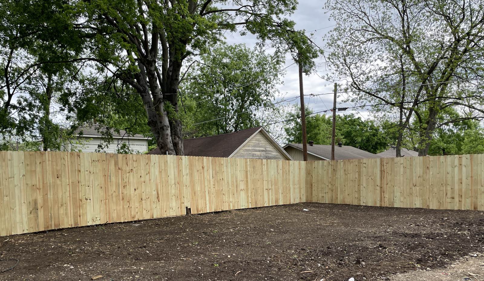 Newly installed natural wood privacy fence around a freshly graded backyard in North Texas