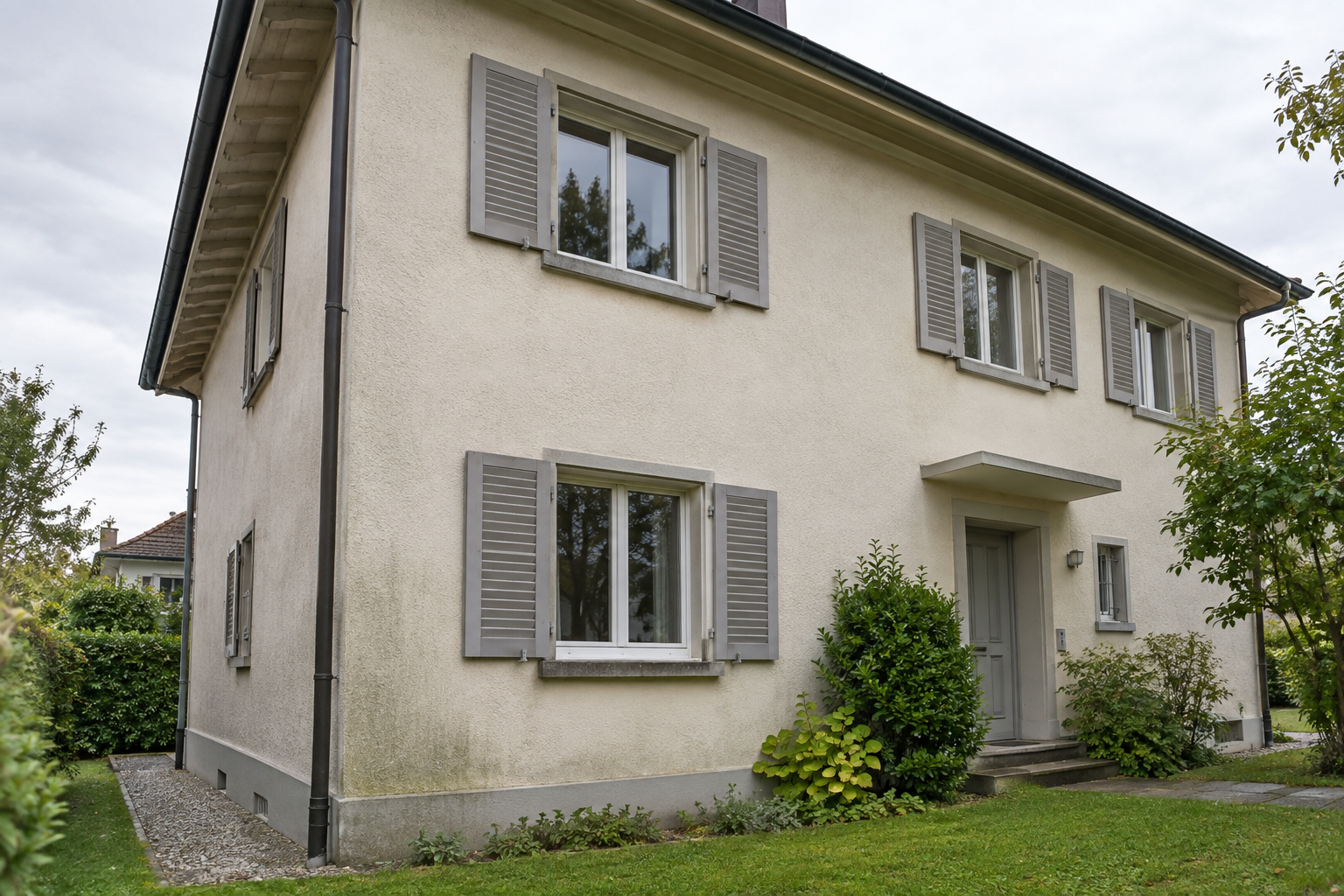 Beispiel einer hellen Hausfassade mit natürlichen Verschmutzungen und leichtem Grünbelag
