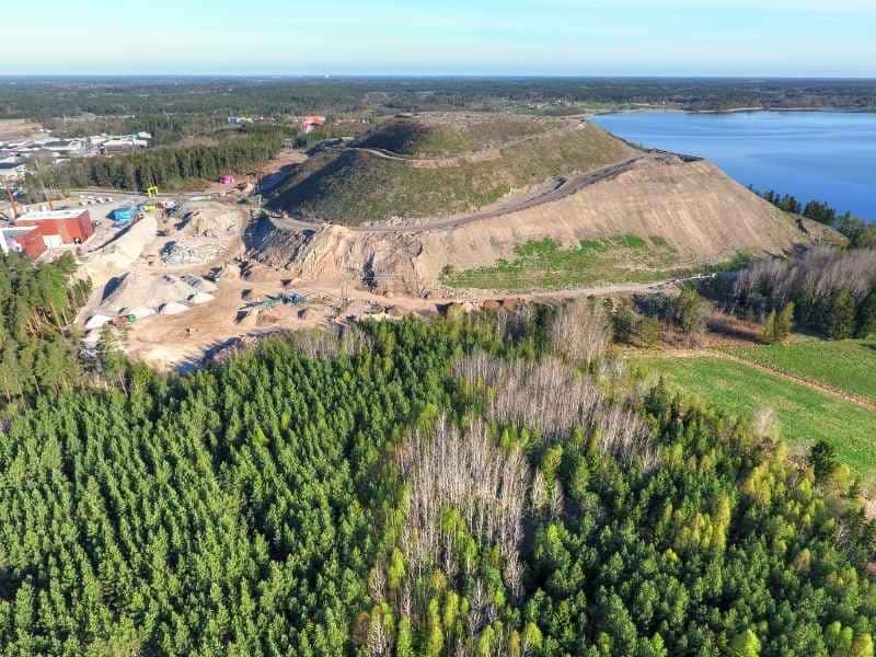 Drone aerial view of a large construction site showing terrain, slopes, and surrounding vegetation