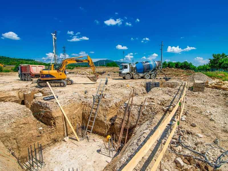 Excavators, concrete mixer truck, and exposed soil at an active construction site in Alabama, showing excavation and ground conditions relevant to LiDAR surveying and earthwork estimates.