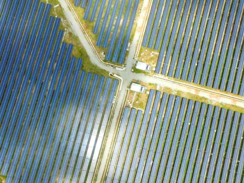 Aerial view of access roads intersecting between large solar panel arrays at a utility-scale solar farm in Texas.