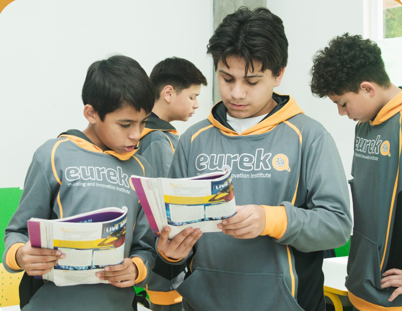 Cuatro alumnos de Eureka con sudadera del instituto revisando sus libros
