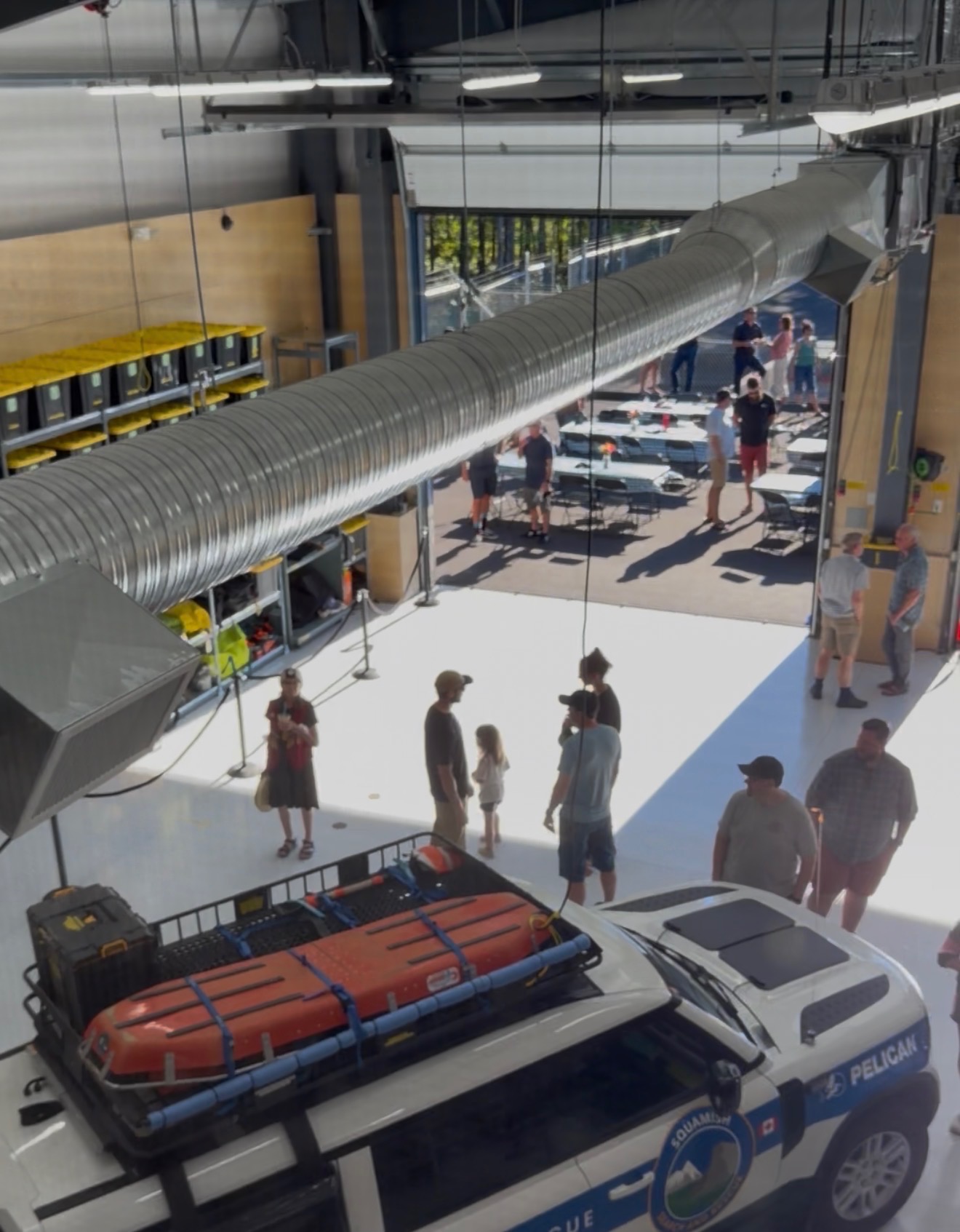 Interior of the new Squamish Search and Rescue building with a rescue truck, equipment, and community members celebrating at the opening.
