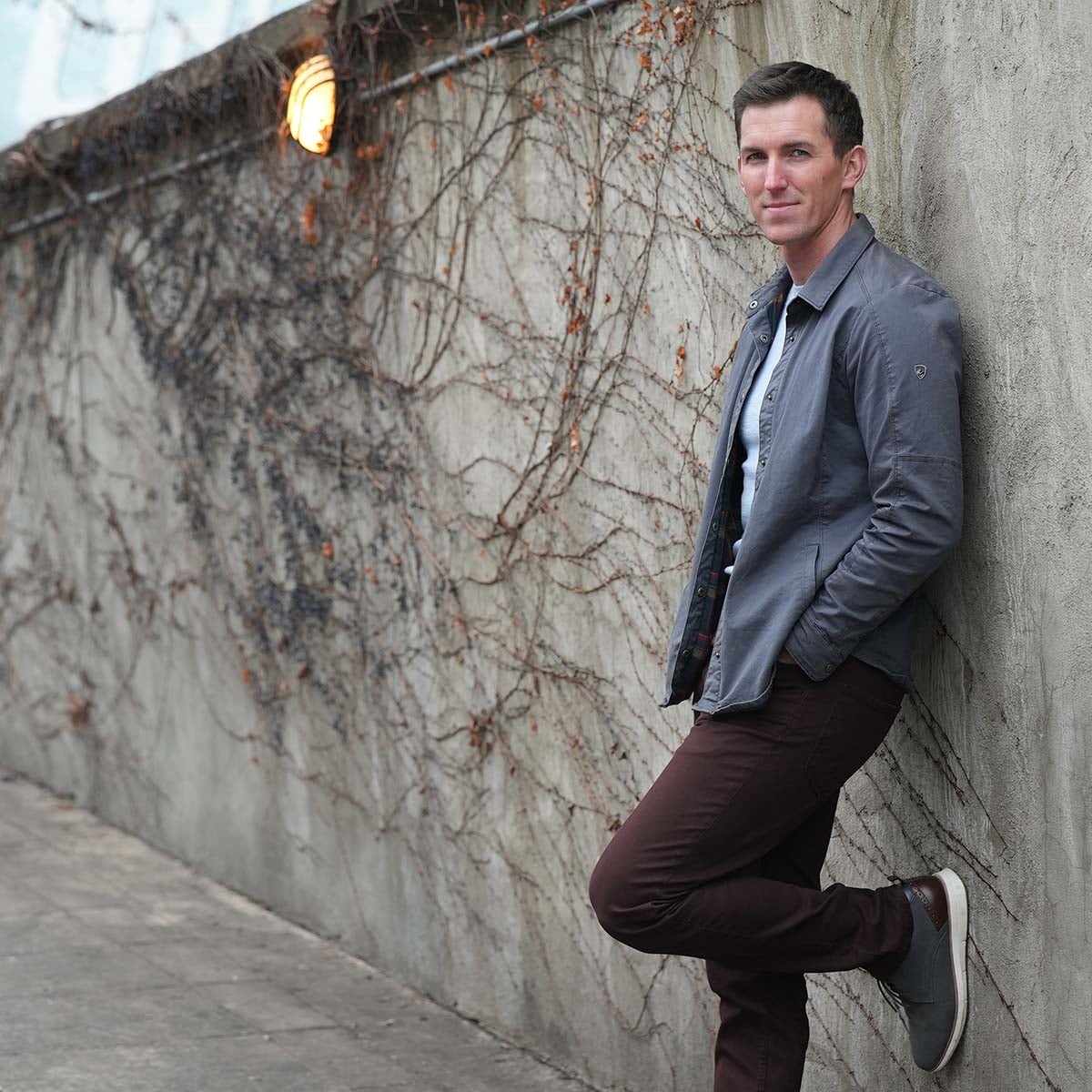 Caleb Nelson leaning against a vine-covered wall