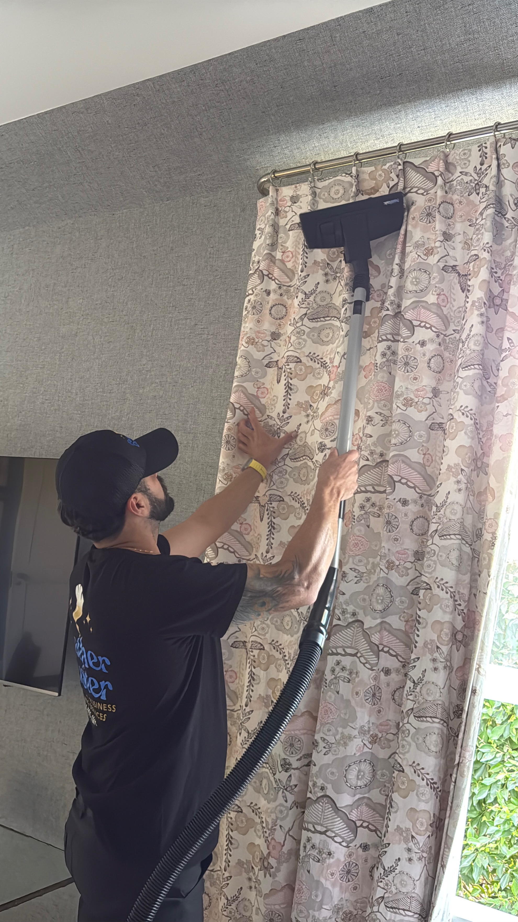 Feather Duster team member detailing patterned drapery in a residential living room