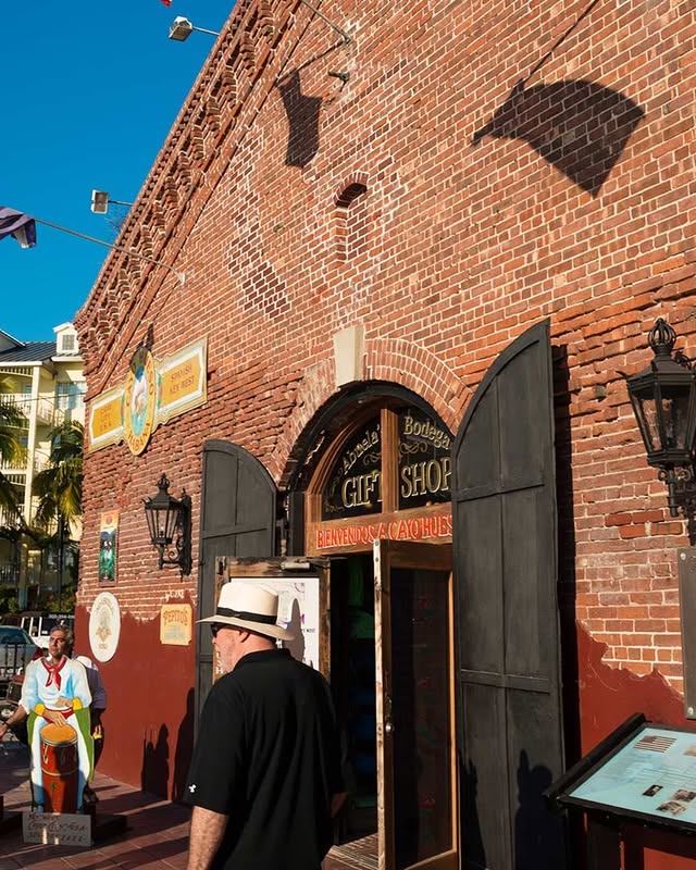 Historic brick facade of El Mesón de Pepe, featuring a gift shop entrance and a man in a hat, capturing Key West's vibrant culture.