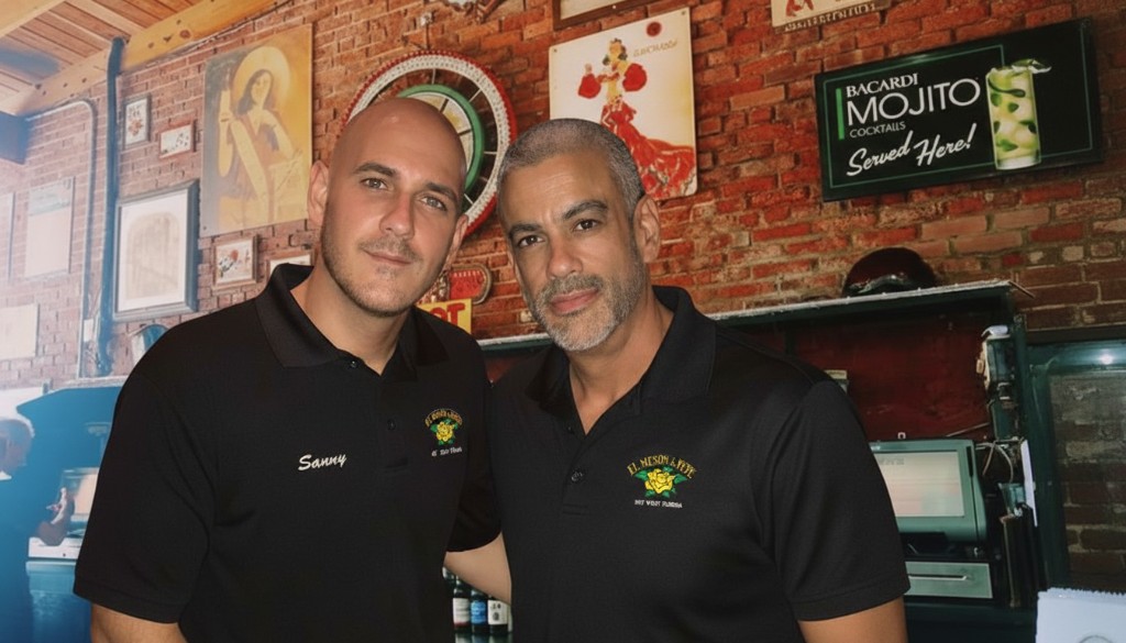 Two co-owners of El Meson de Pepe in Key West, wearing branded shirts, with a vibrant Cuban-themed background.
