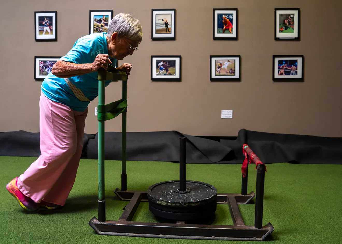 senior woman pushing sled in gym