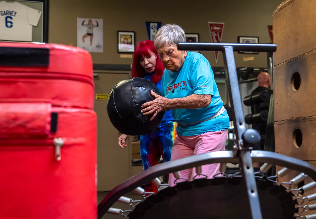 senior woman throwing medicine ball against trampoline
