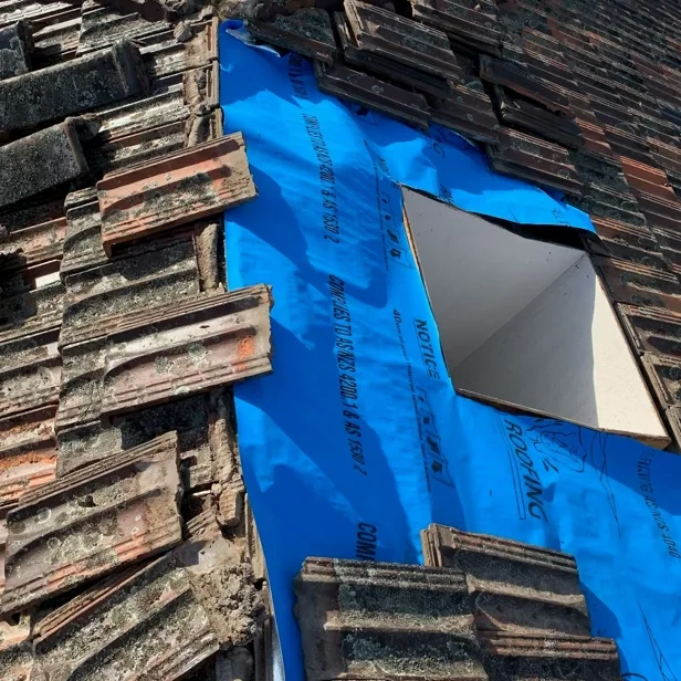 Professional emergency roof repairs Melbourne - leak repair on damaged terracotta tile roof with blue tarp