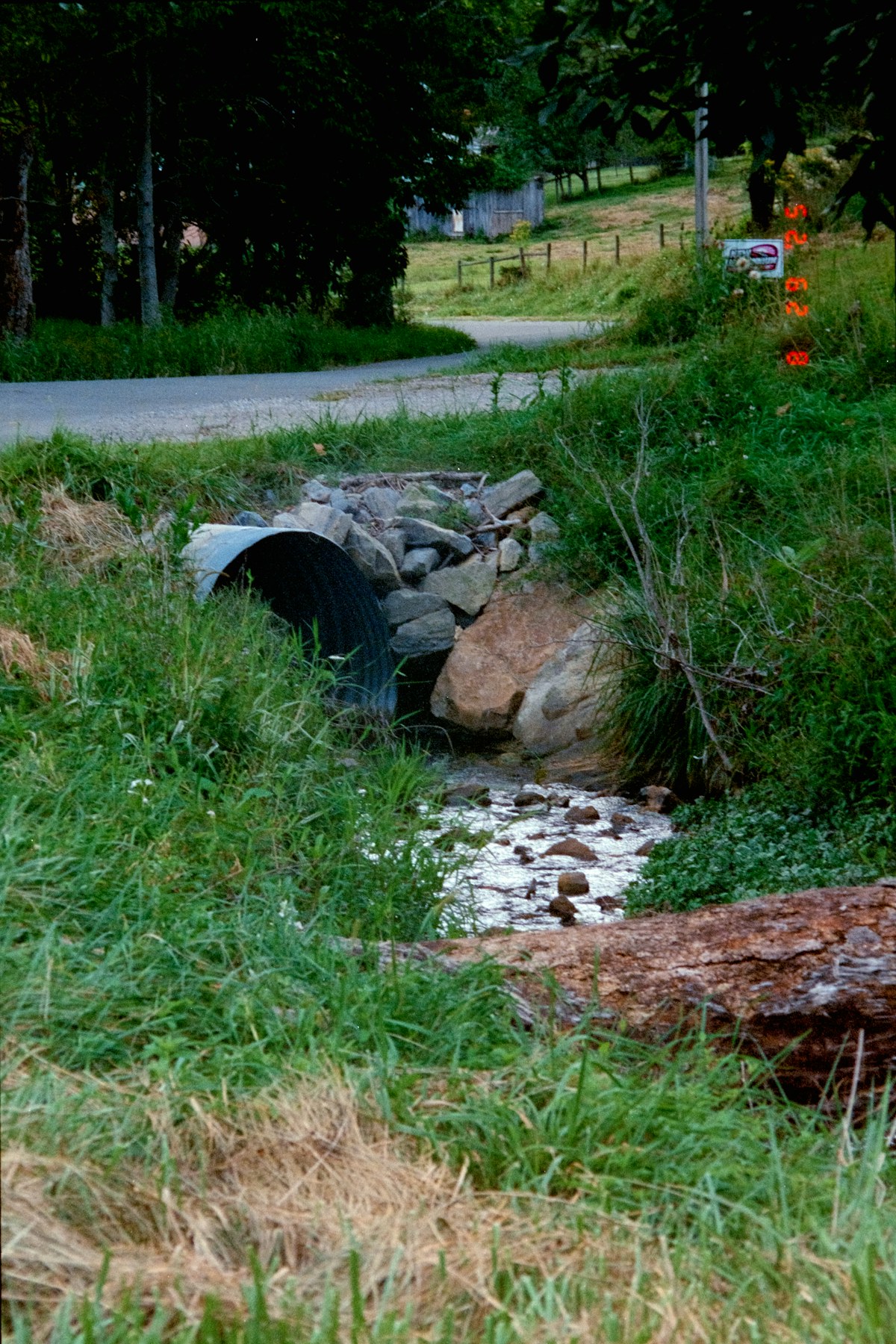 Roadside culvert and creek illustrating drainage questions for a home on a private road.