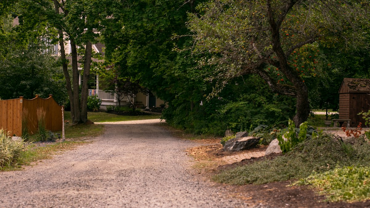 Gravel driveway approaching a home, illustrating why buyers should confirm who maintains a shared private road.