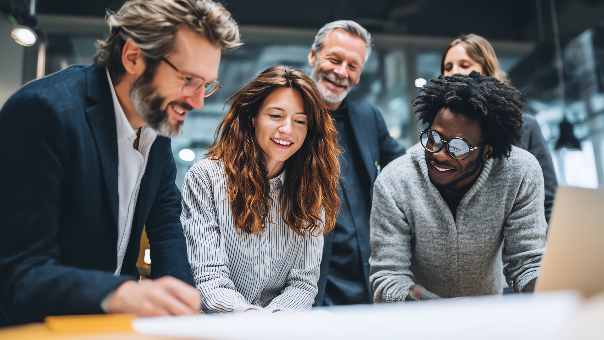 Smiling team collaborating around a laptop in a modern office