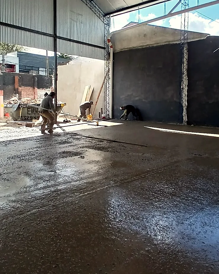 Operarios trabajando en el frente de obra junto al muro del fondo del galpón.