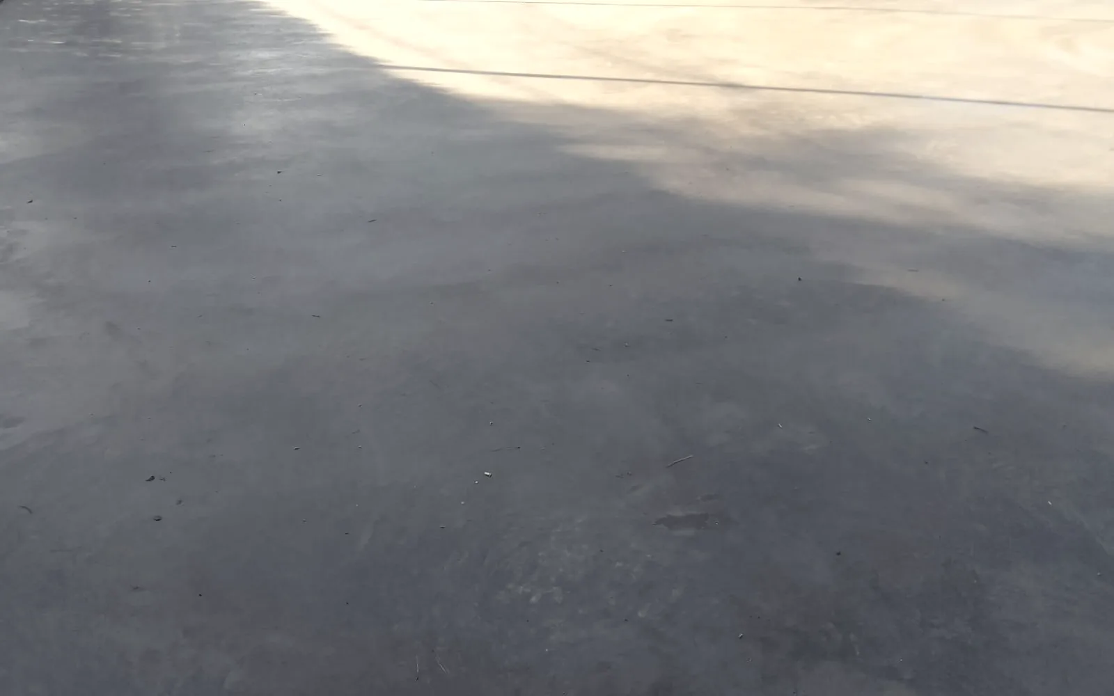 Superficie exterior de hormigón alisado ya terminada, con la luz de la tarde sobre una parte del piso y las juntas a lo lejos.